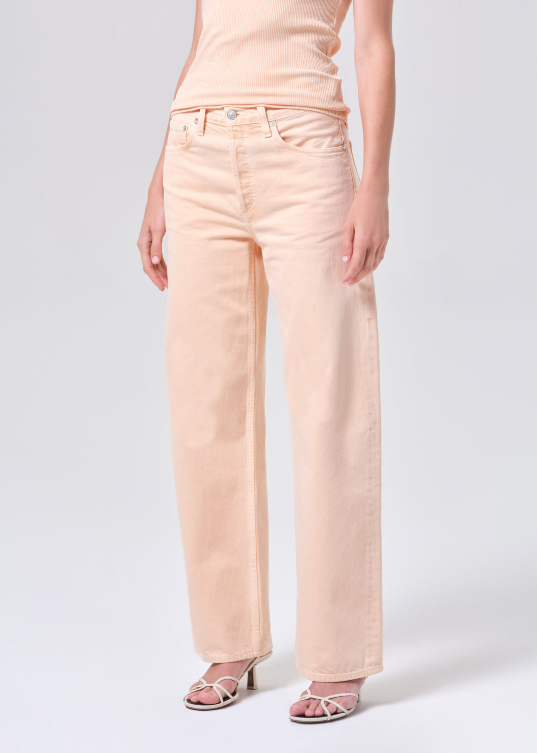 Person wearing light pink jeans on a white background