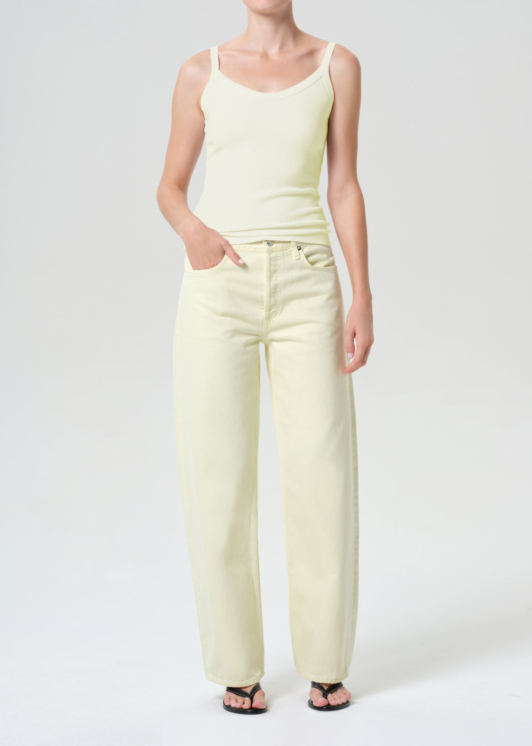 Person wearing a light green tank top and pants on a white background