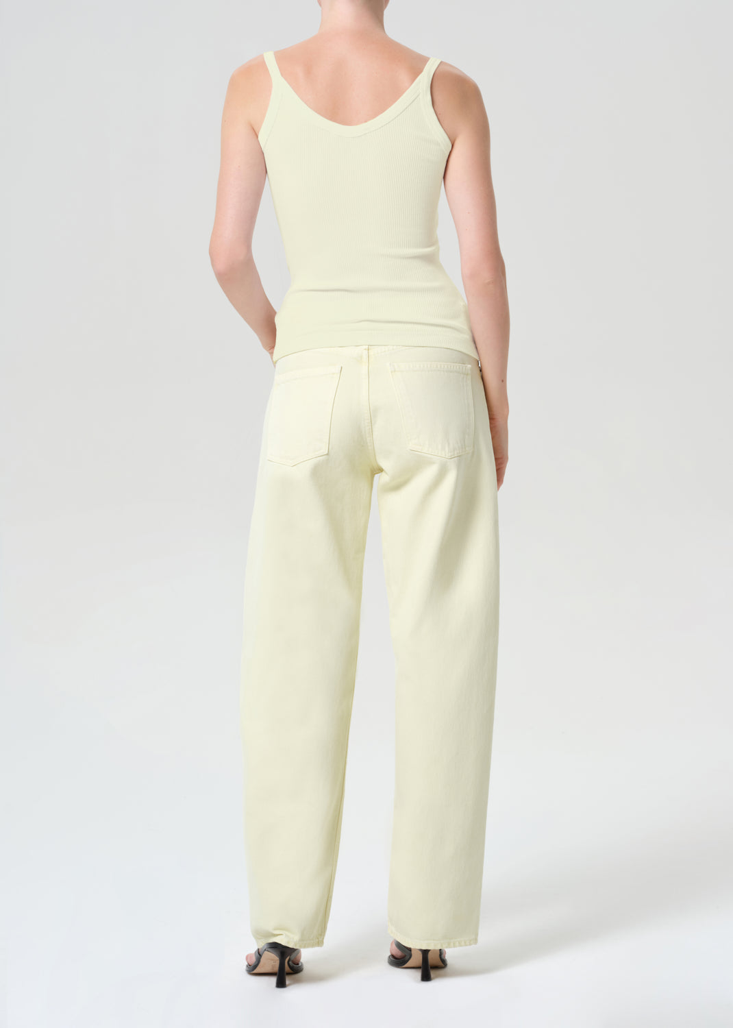Person wearing a light yellow jumpsuit on a white background