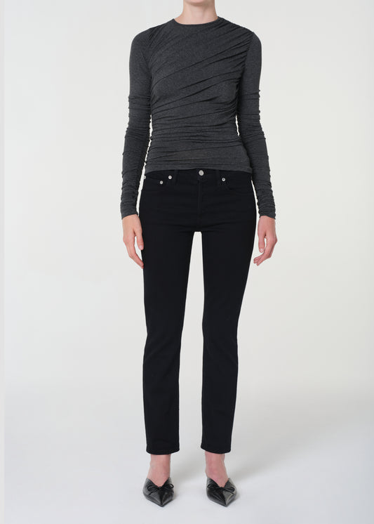 Person wearing a black ruched top and black pants on a white background