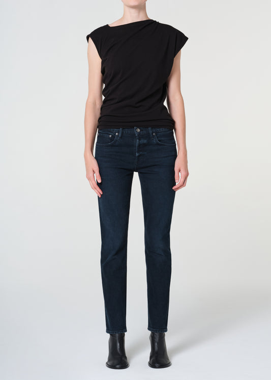 Person wearing a black sleeveless top and dark blue jeans on a white background