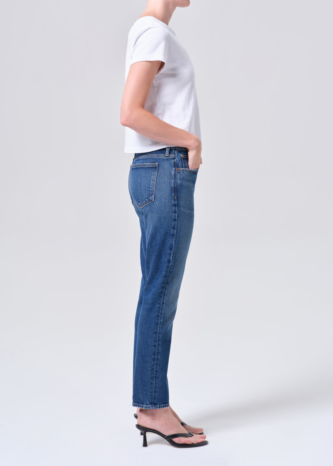 Person wearing blue jeans and a white t-shirt on a white background