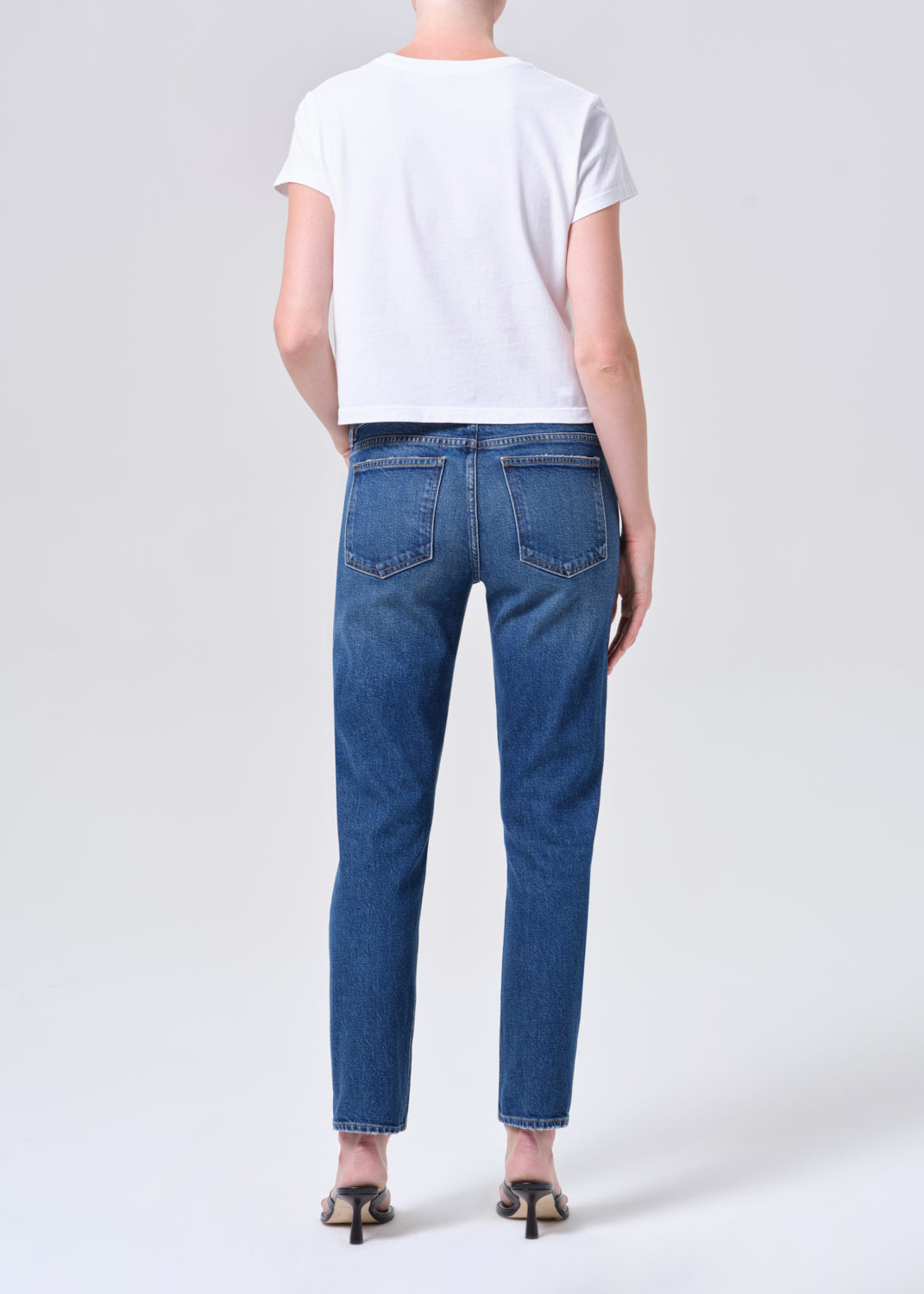 Person wearing blue jeans and a white t-shirt on a plain background