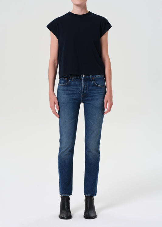 Person wearing a black sleeveless top and blue jeans on a white background