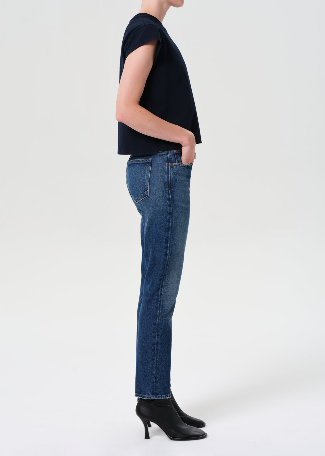 Person wearing a black top and blue jeans on a white background
