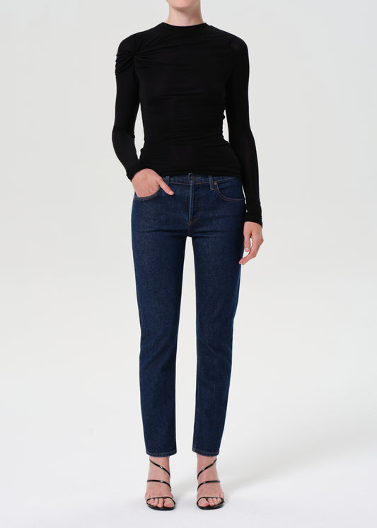 Person wearing a black long-sleeve top and dark blue jeans on a white background