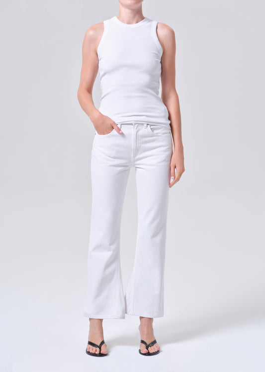 Person wearing a white sleeveless top and white pants on a light gray background