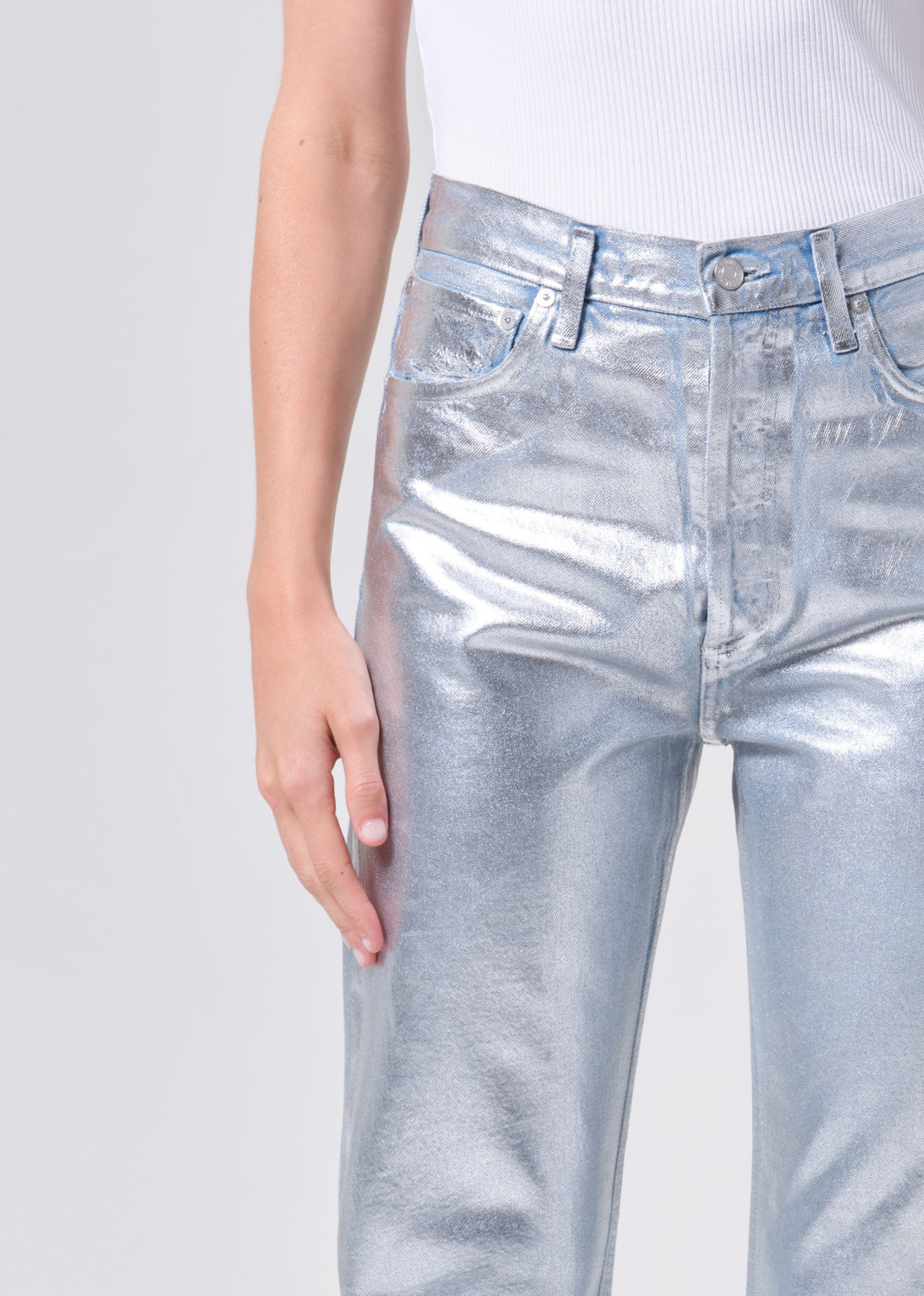 Silver metallic jeans worn by a person on a light gray background