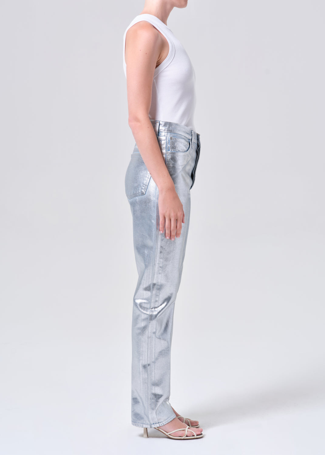 Person wearing light blue jeans and a white top on a plain background