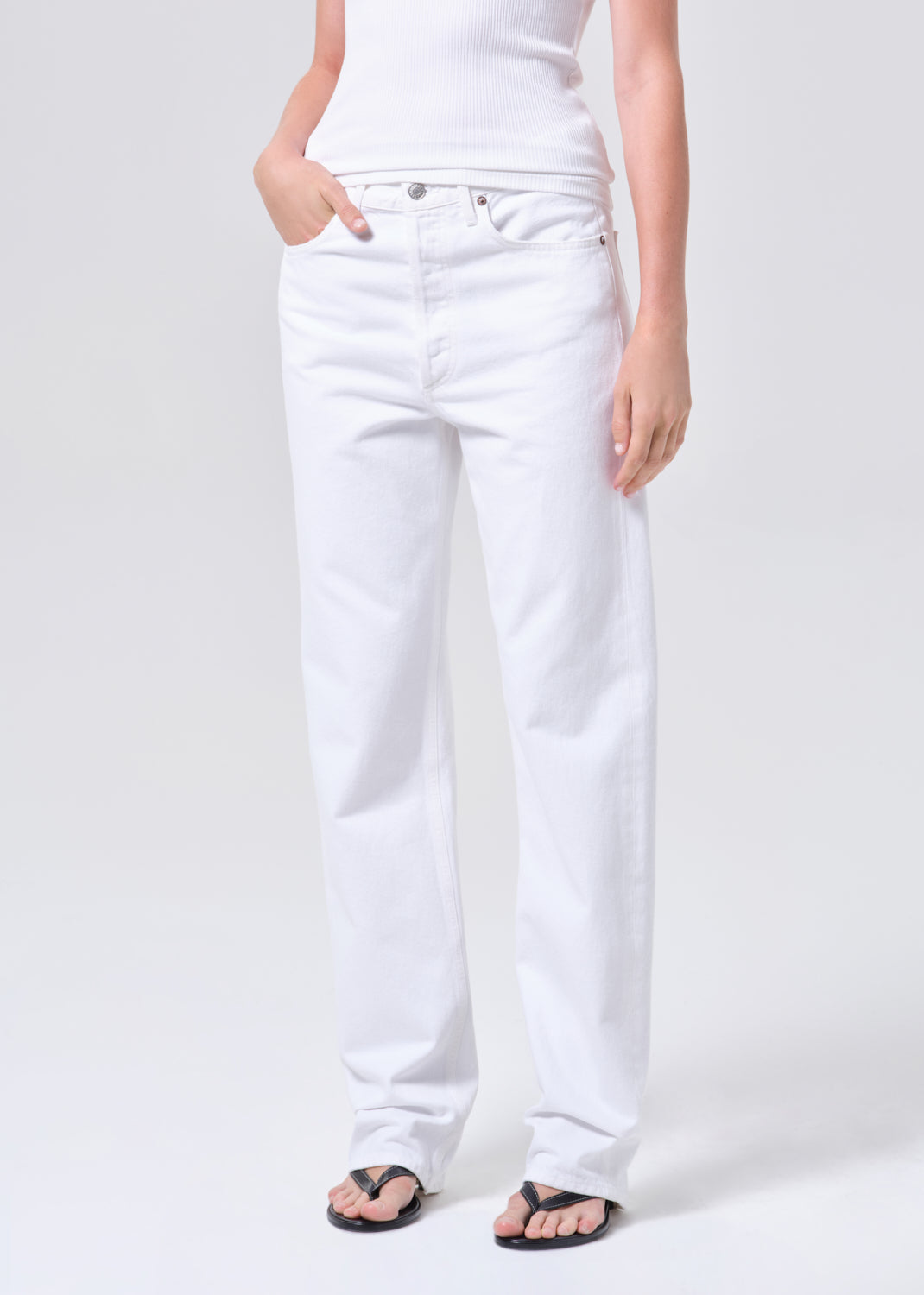 Person wearing white jeans on a plain background