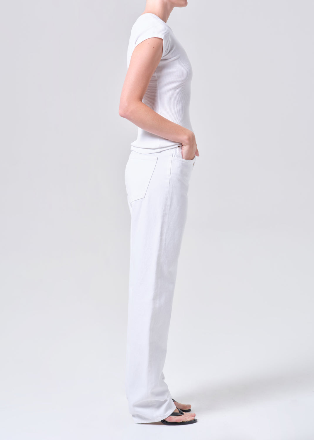Person wearing a white t-shirt and pants on a plain background