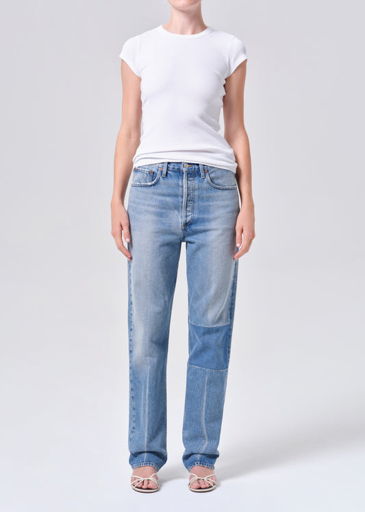 Person wearing light blue jeans and a white t-shirt on a plain background