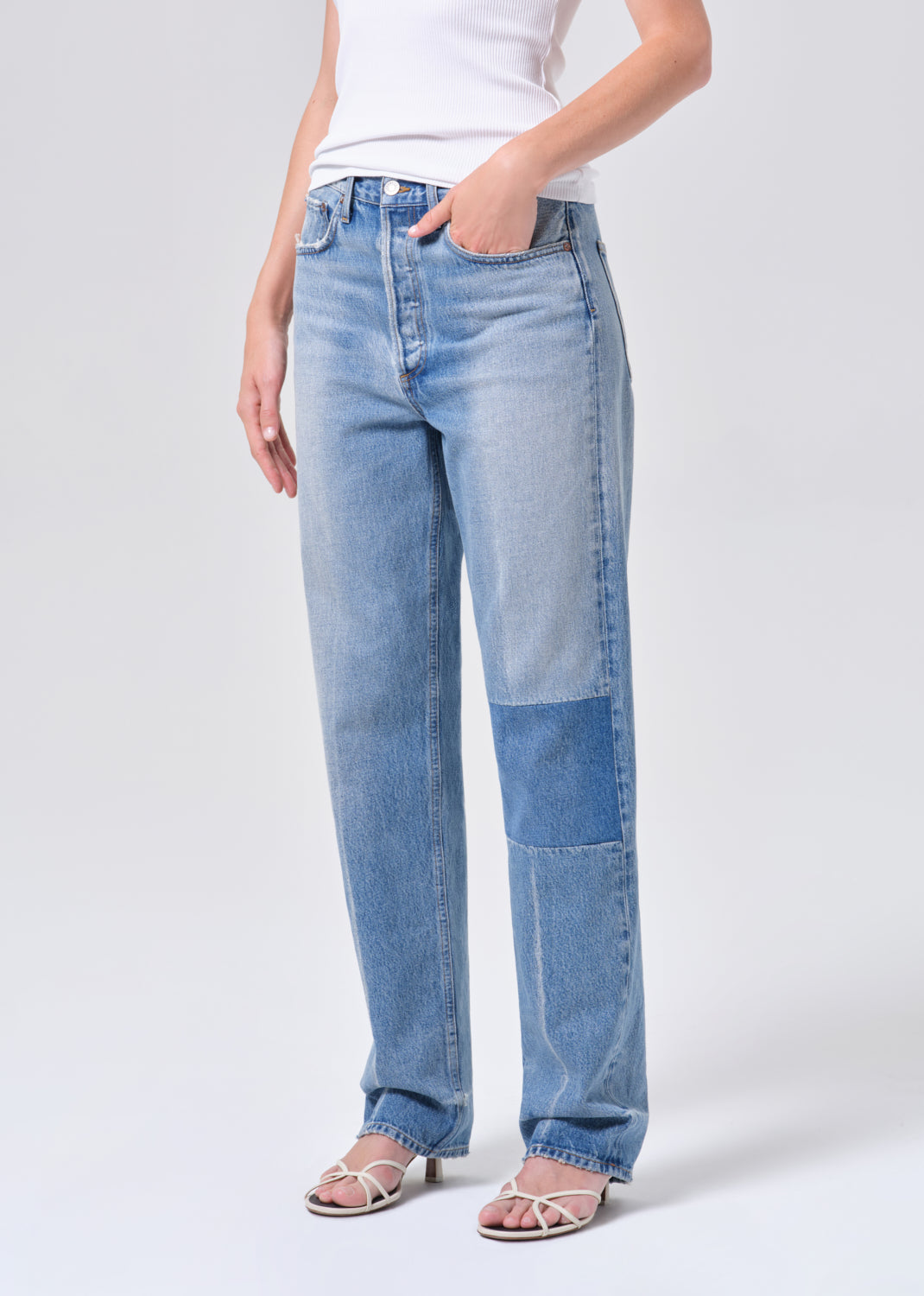 Light blue patchwork jeans worn by a person on a white background