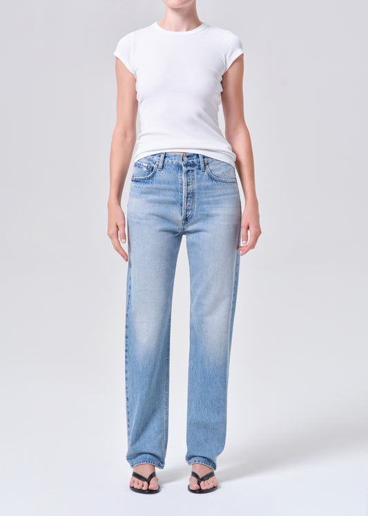 Person wearing light blue jeans and a white t-shirt on a plain background