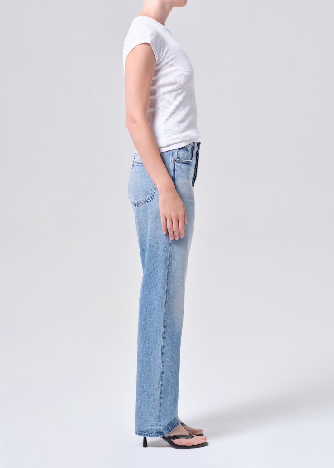 Person wearing light blue jeans and a white t-shirt on a plain background