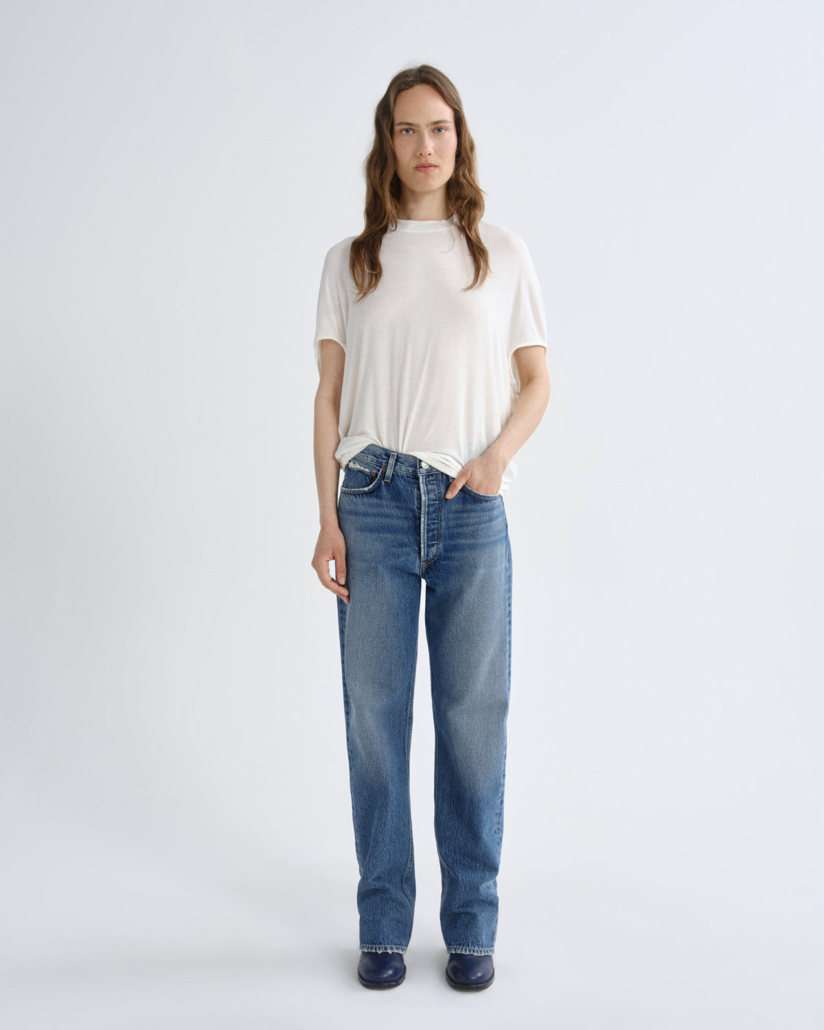 Woman wearing a white t-shirt and blue jeans on a white background