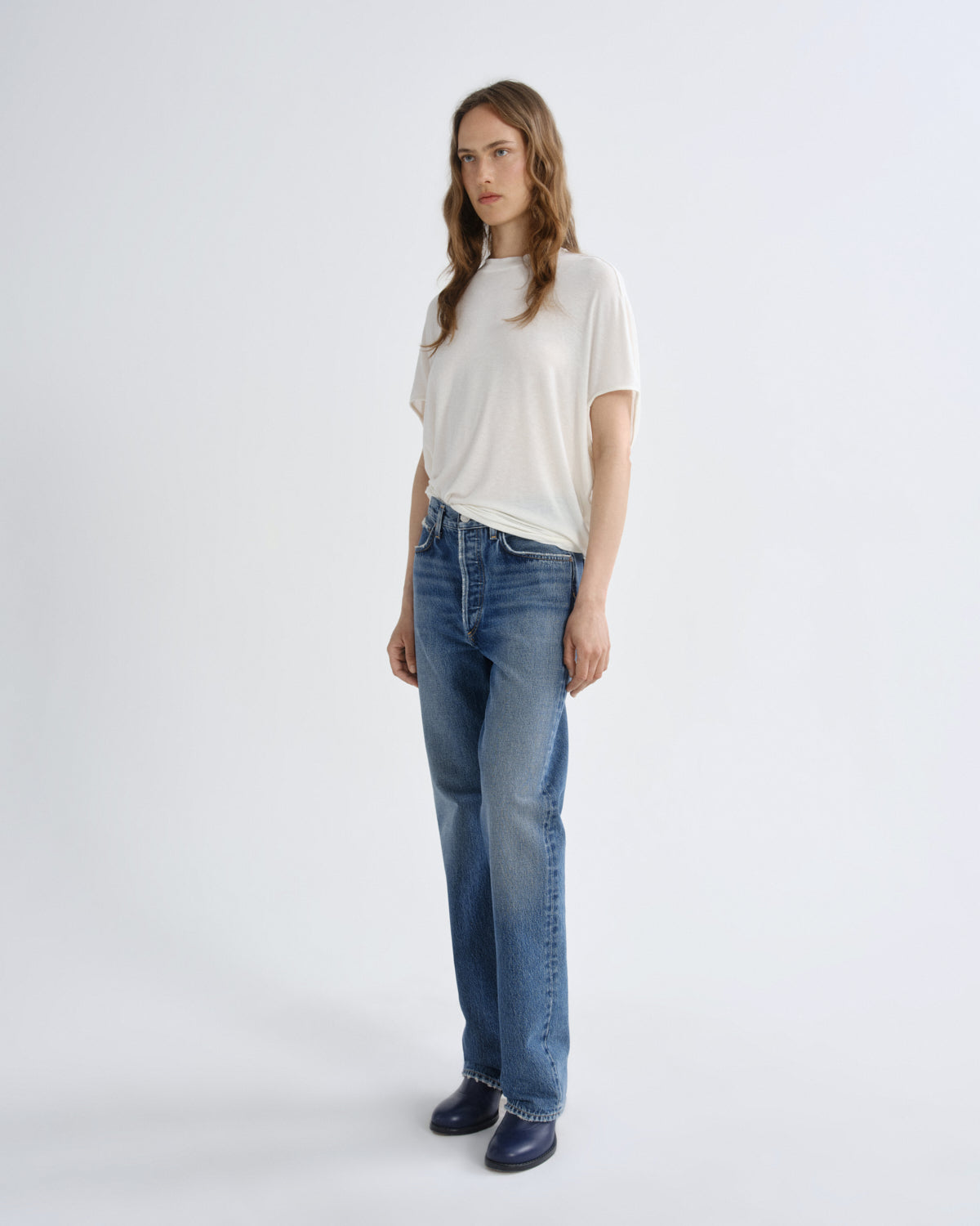 Woman wearing a white t-shirt and blue jeans on a white background