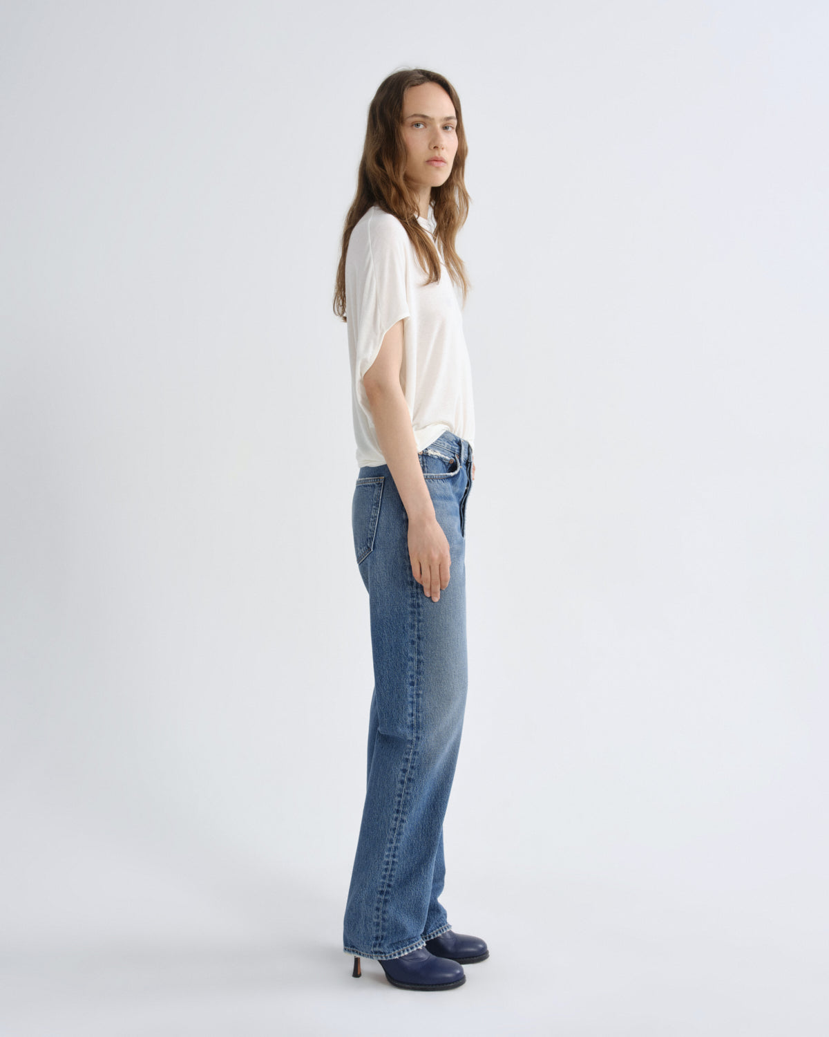 Woman wearing a white top and blue jeans on a white background