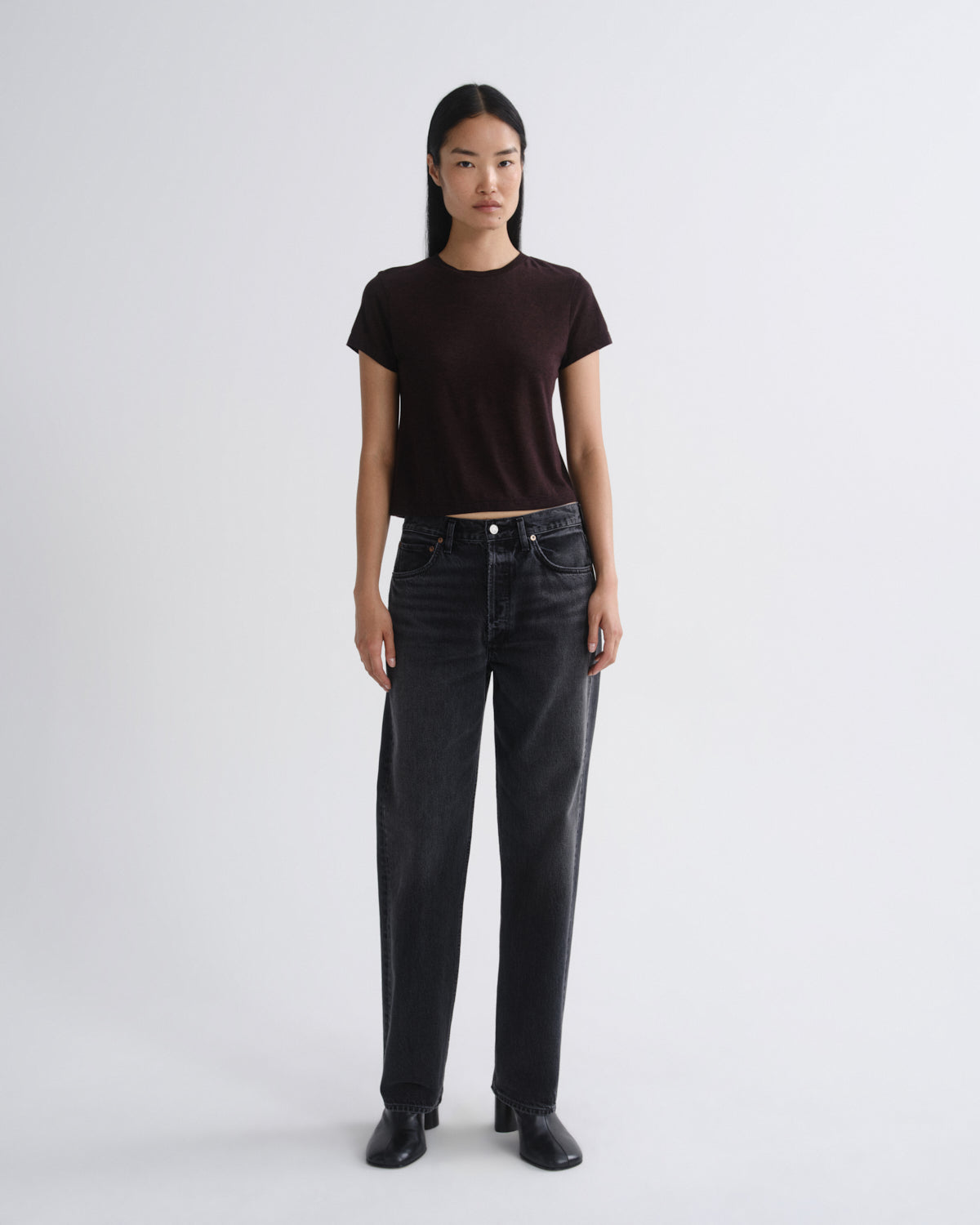Person wearing a black t-shirt and dark jeans on a white background