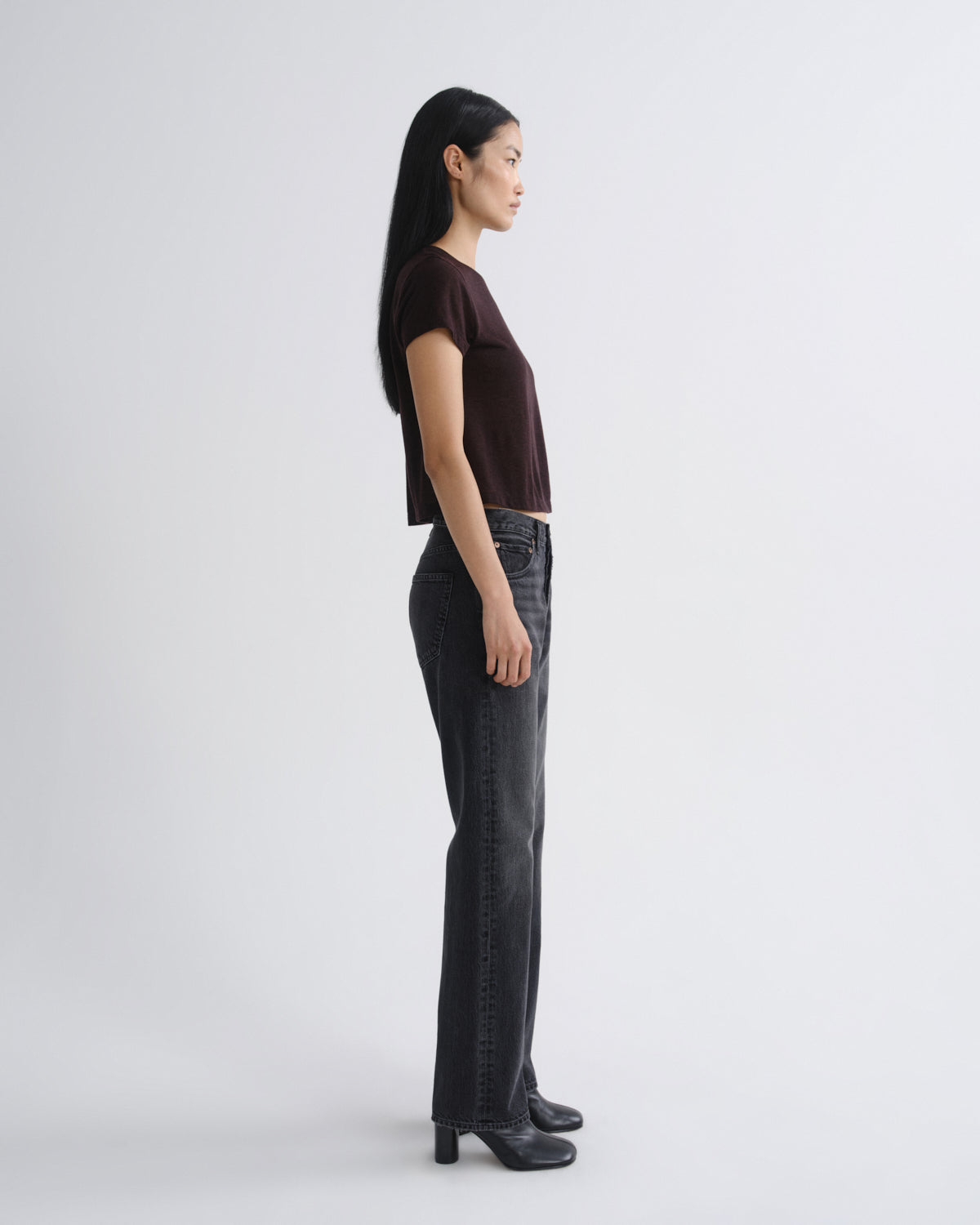 Woman wearing a dark brown top and black pants on a white background