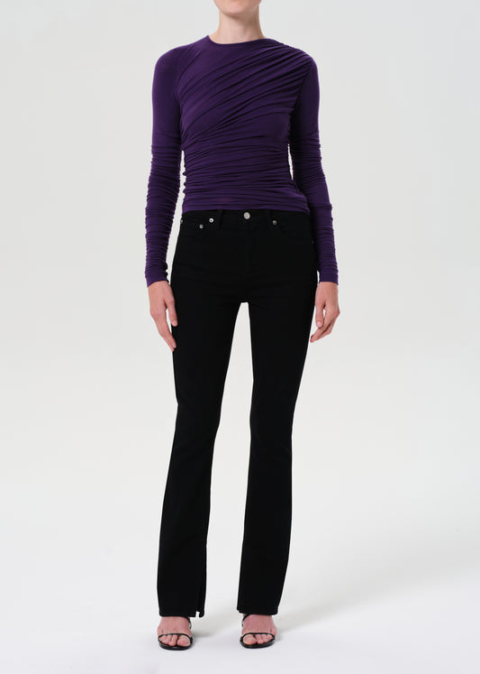 Person wearing a purple long-sleeve top and black pants on a white background