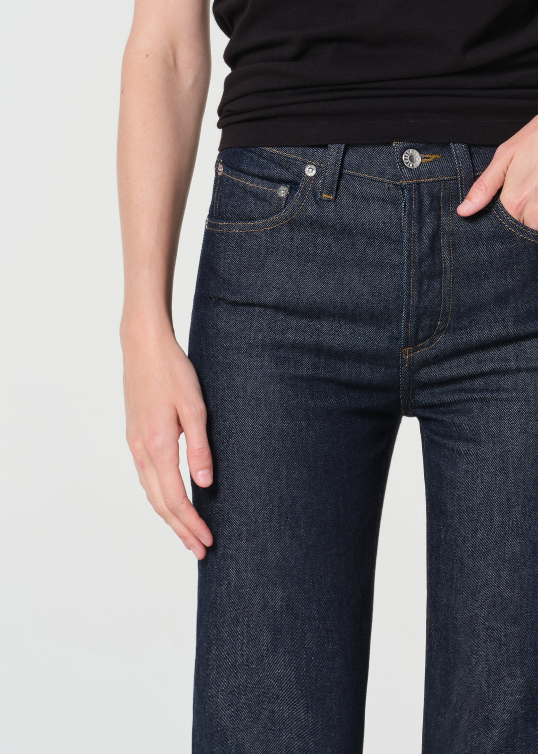 Dark blue jeans worn by a person on a light gray background
