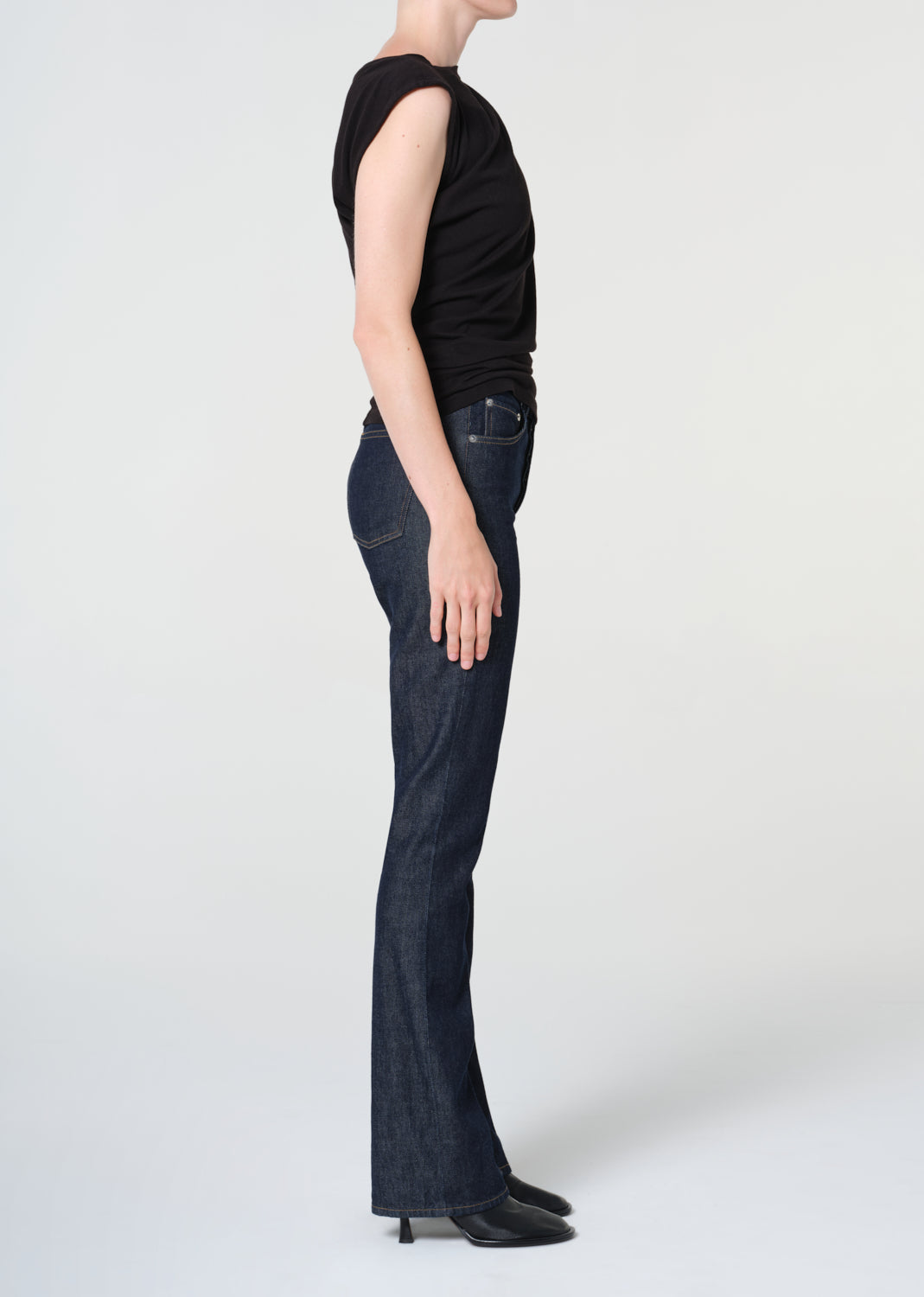 Person wearing dark blue jeans and a black top on a white background