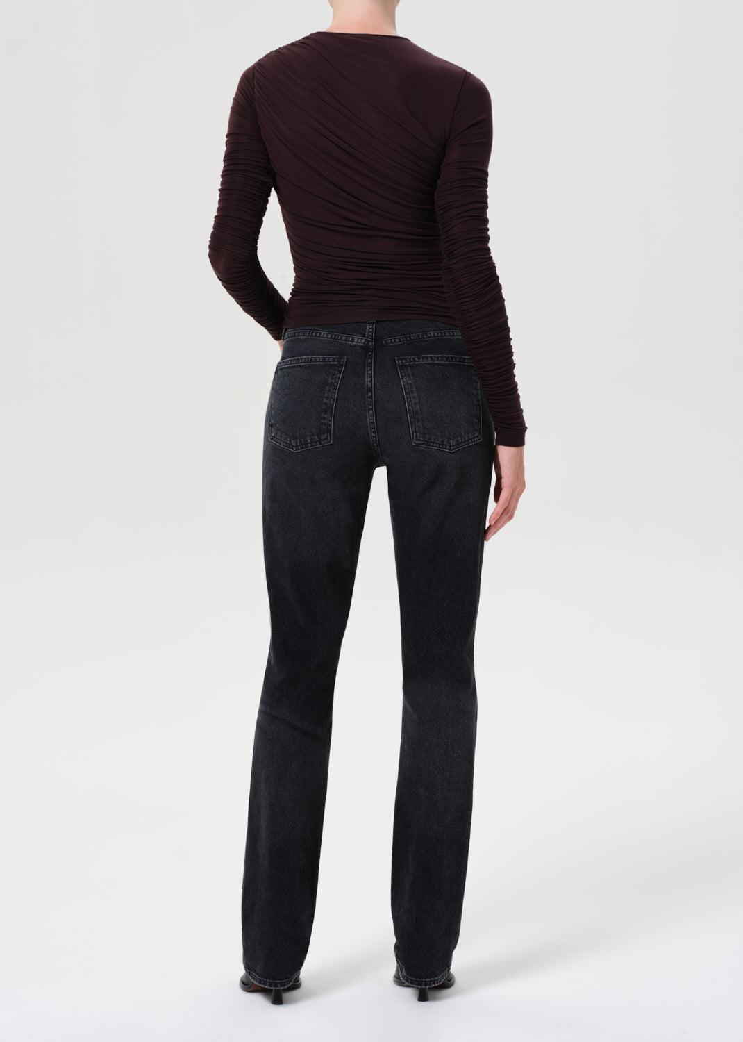 Person wearing black jeans and a dark long-sleeve shirt on a white background