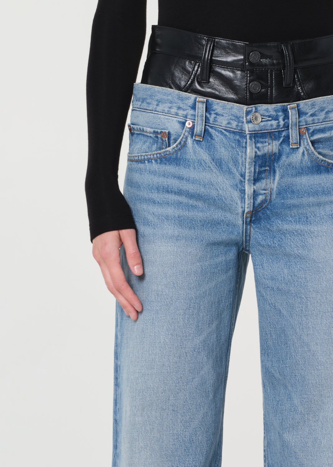 Close-up of blue jeans and a black leather jacket on a light gray background