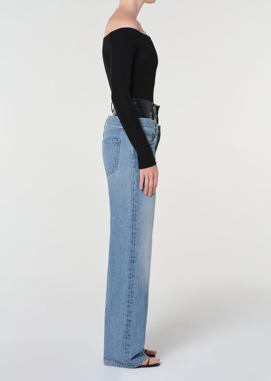 Person wearing light blue jeans and a black top on a white background