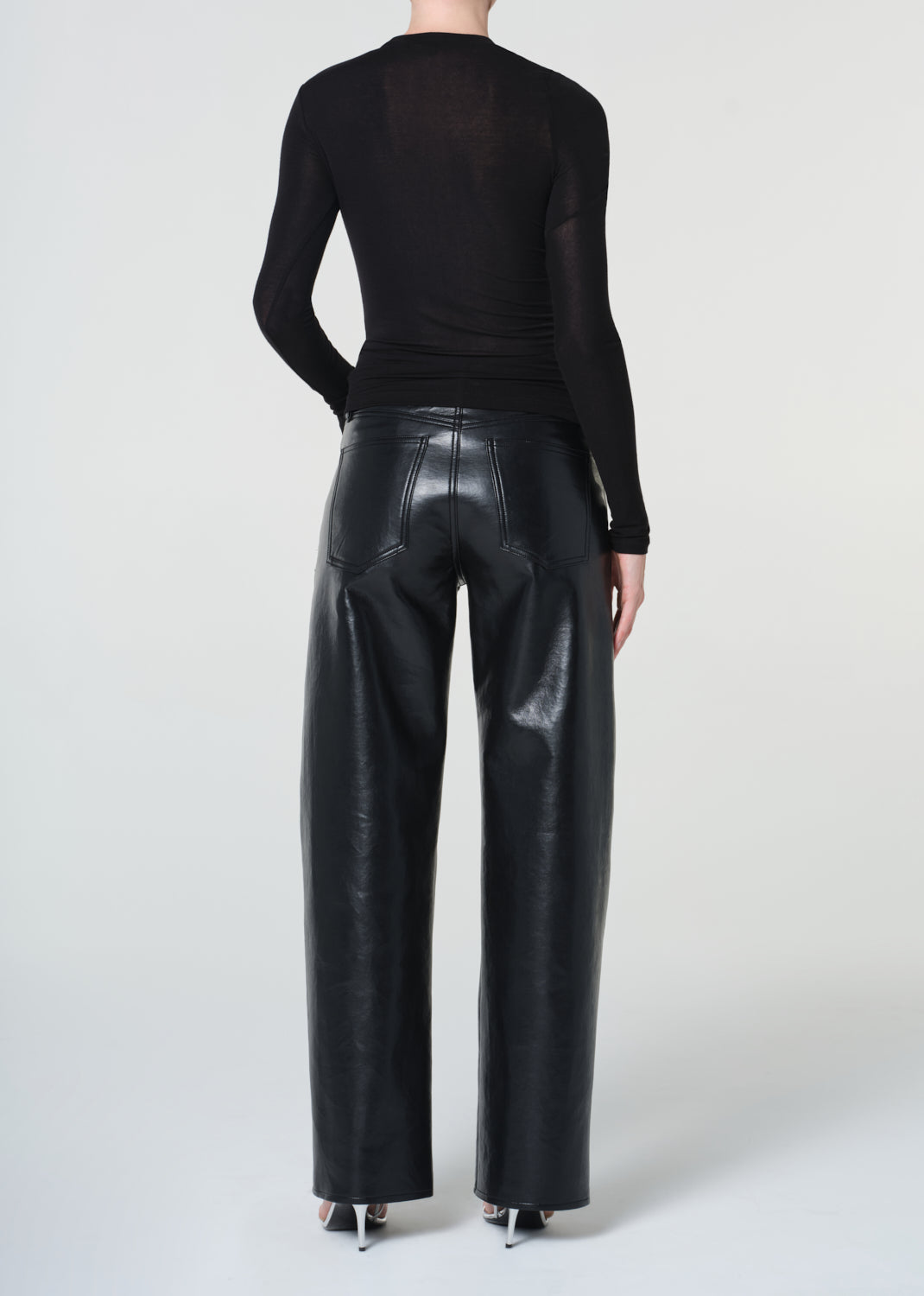 Person wearing black leather pants and a black top on a white background