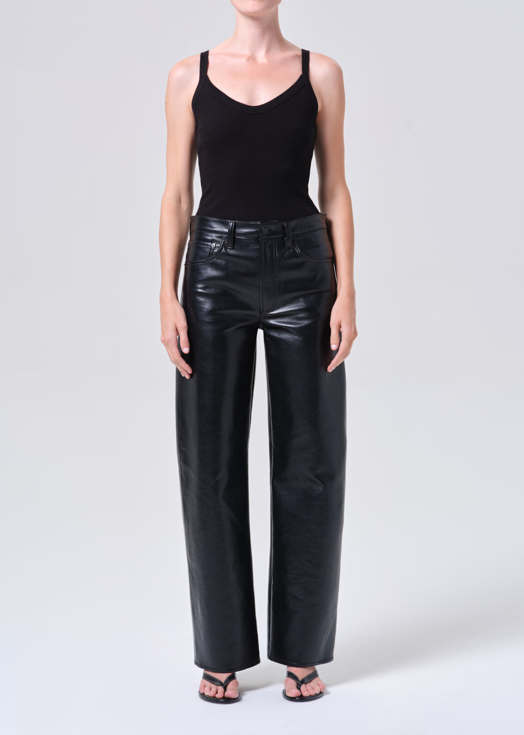 Person wearing a black tank top and black leather pants on a white background