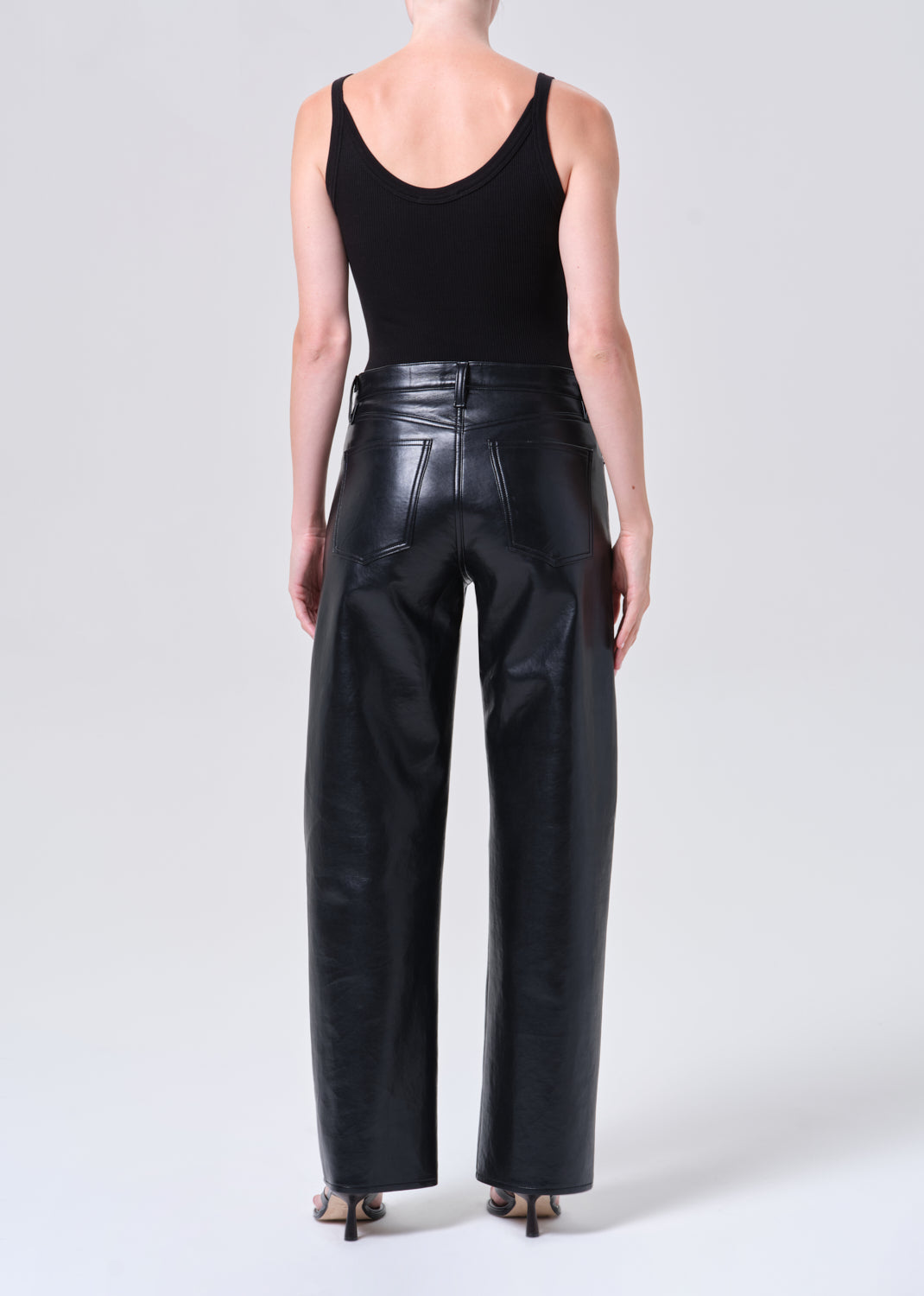 Person wearing black leather pants and a black tank top on a white background
