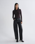 Person wearing a brown long-sleeve top and black leather pants on a white background