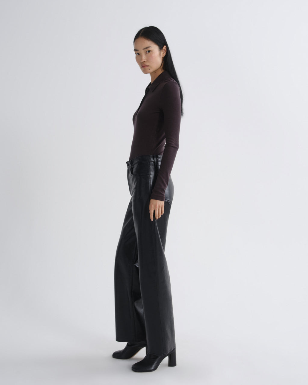 Person wearing a dark outfit with a high-waisted black leather skirt on a white background