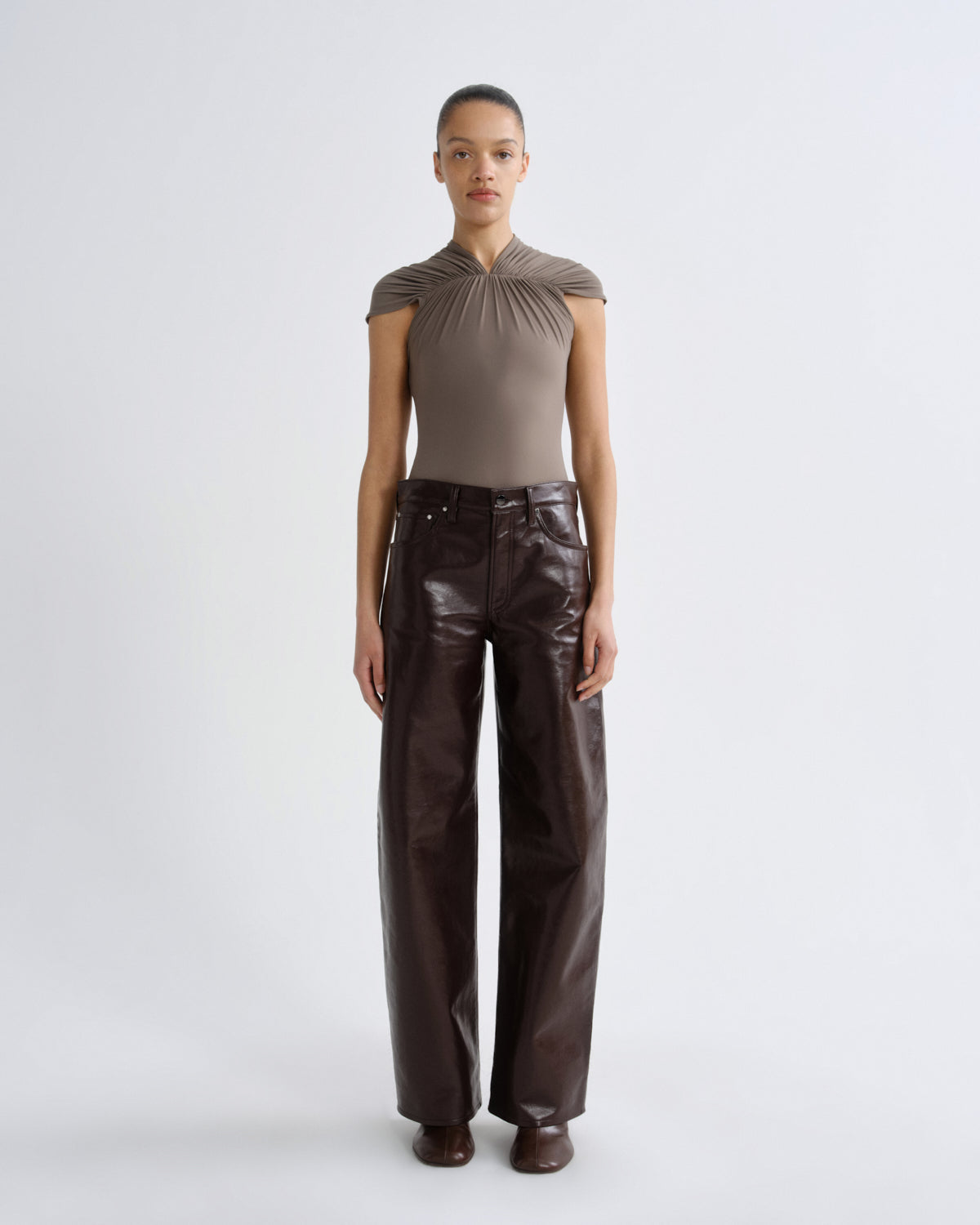 Person wearing a brown top and leather pants on a white background