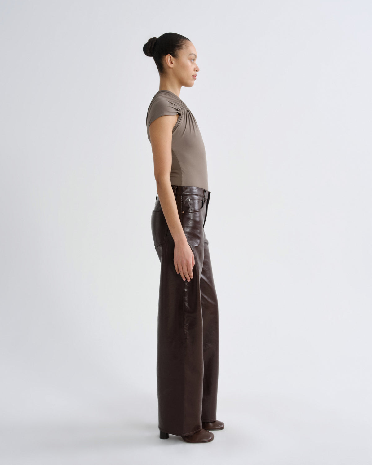 Woman wearing a brown top and dark pants on a white background