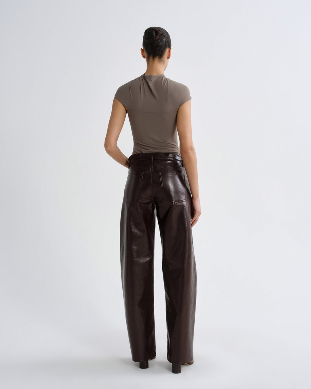 Person wearing brown leather pants and a matching top on a white background