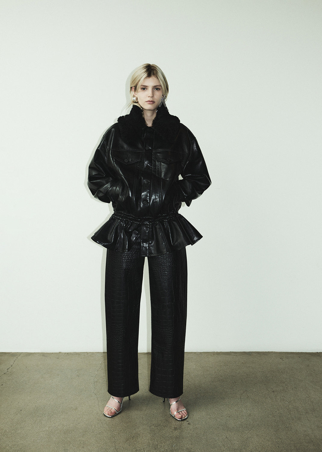 Person wearing a black leather outfit against a white background