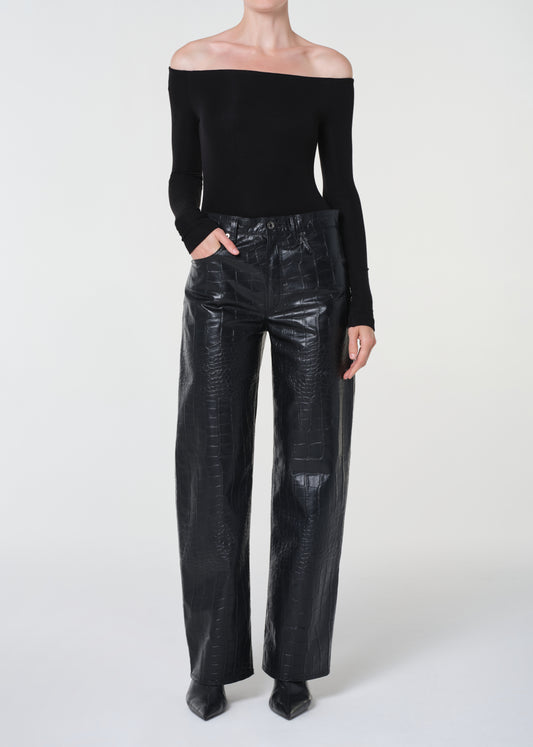 Person wearing a black off-shoulder top and black leather pants on a white background