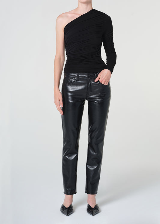 Person wearing a black one-shoulder top and black leather pants on a white background
