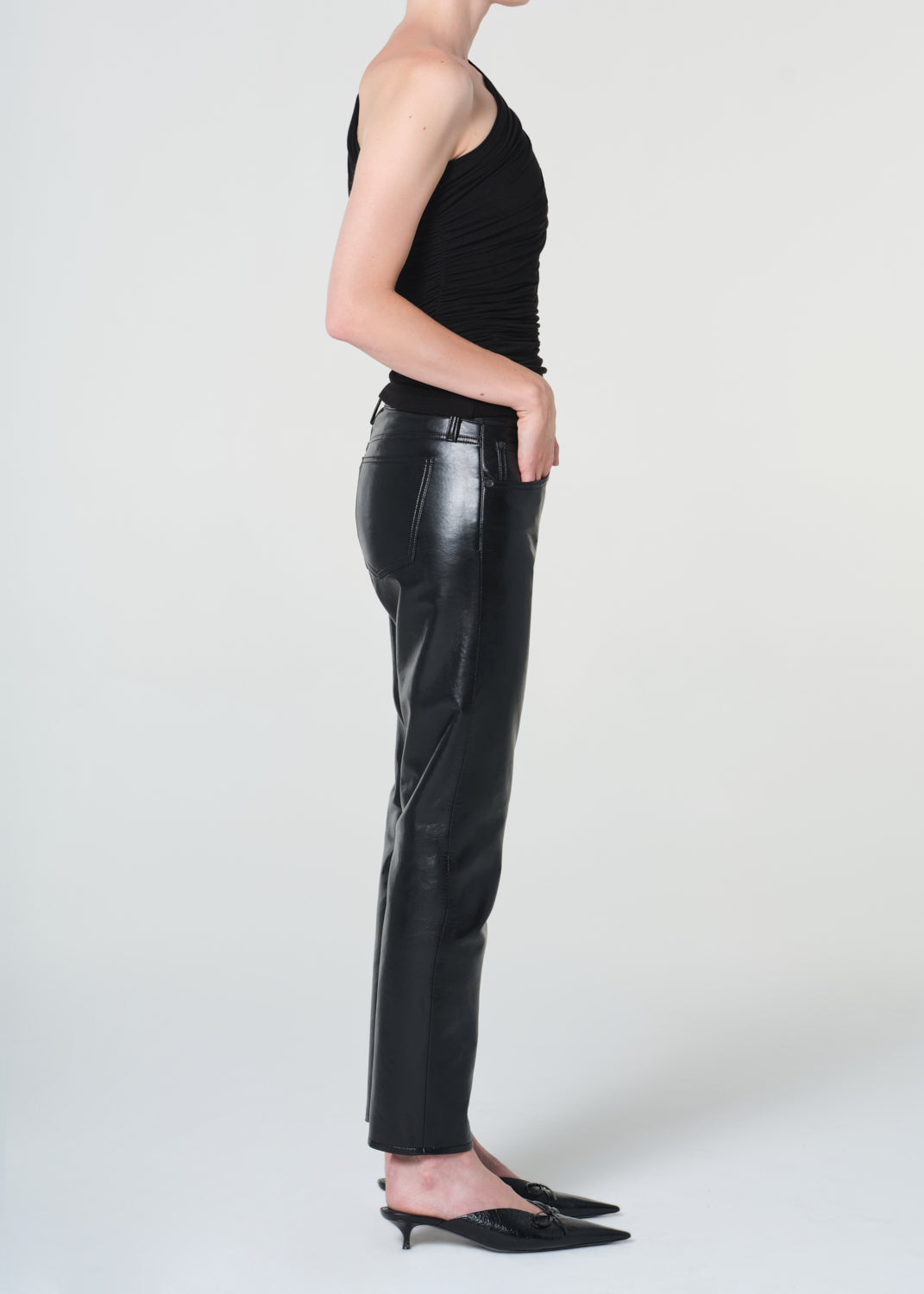 Person wearing black leather pants and a black top on a white background