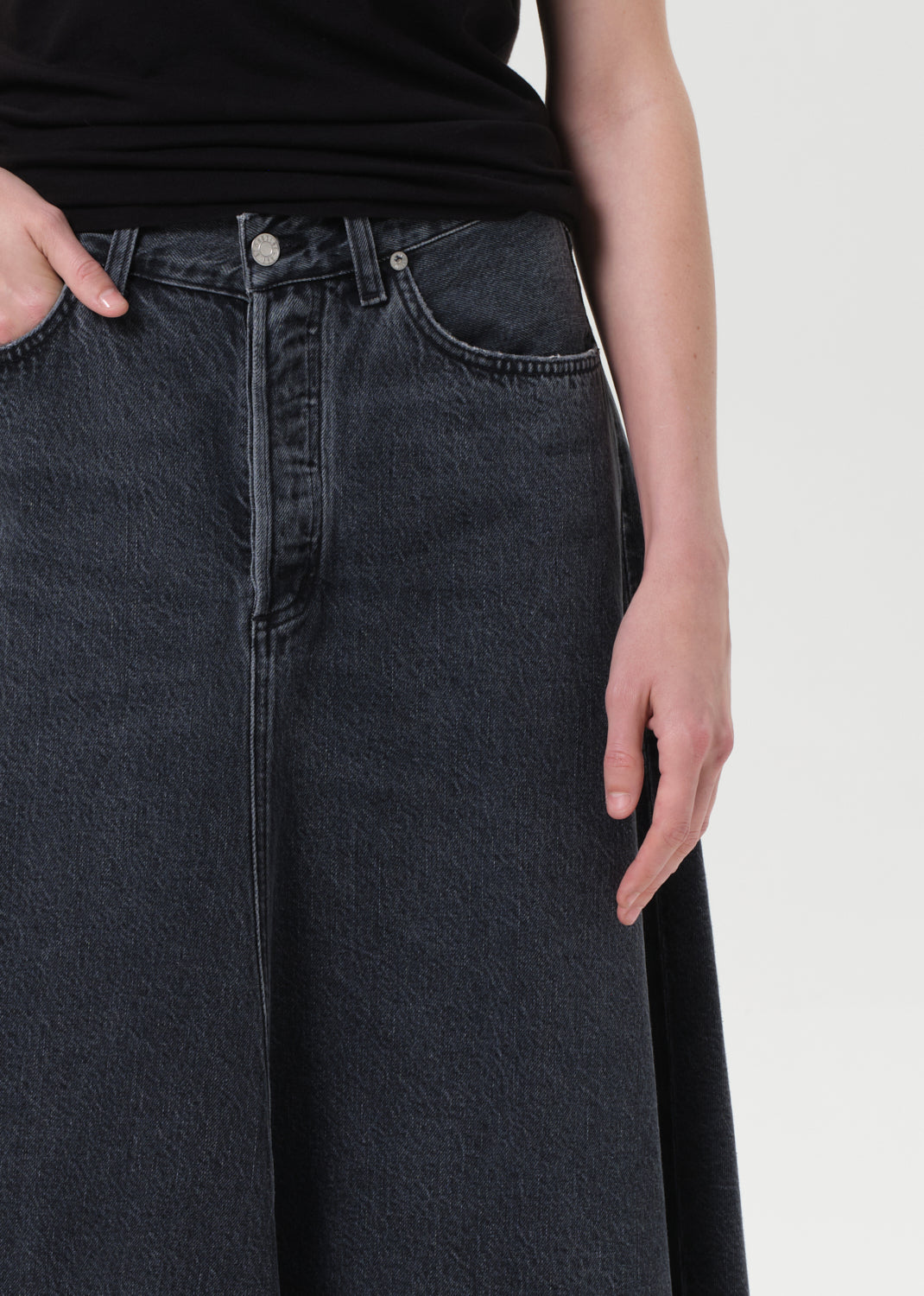 Person wearing dark blue jeans on a plain background
