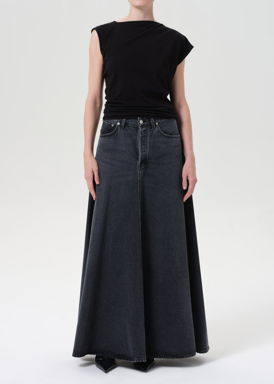 Person wearing a black top and wide-leg jeans on a white background