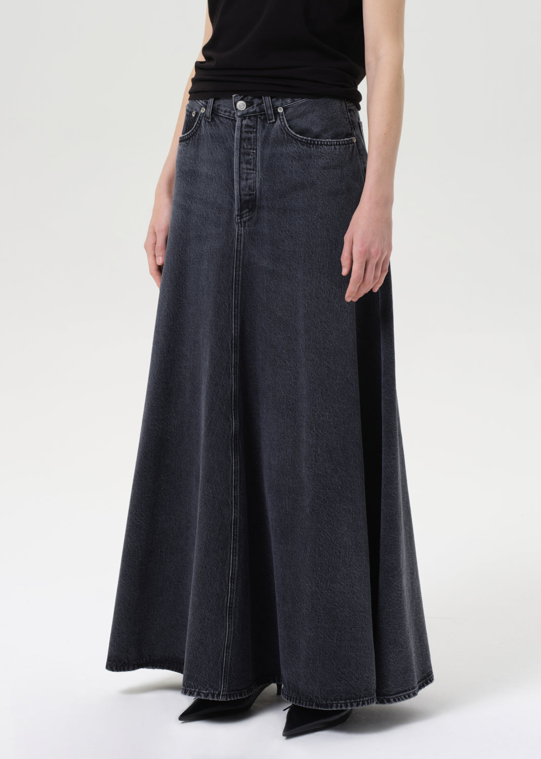 Person wearing a long black denim skirt on a white background