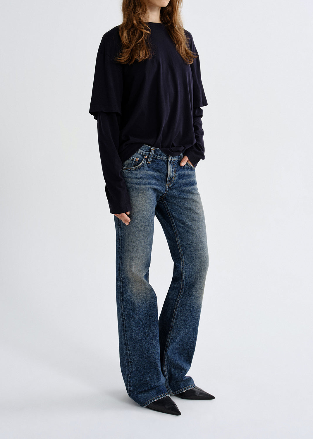Person wearing a black top and blue jeans on a grey background