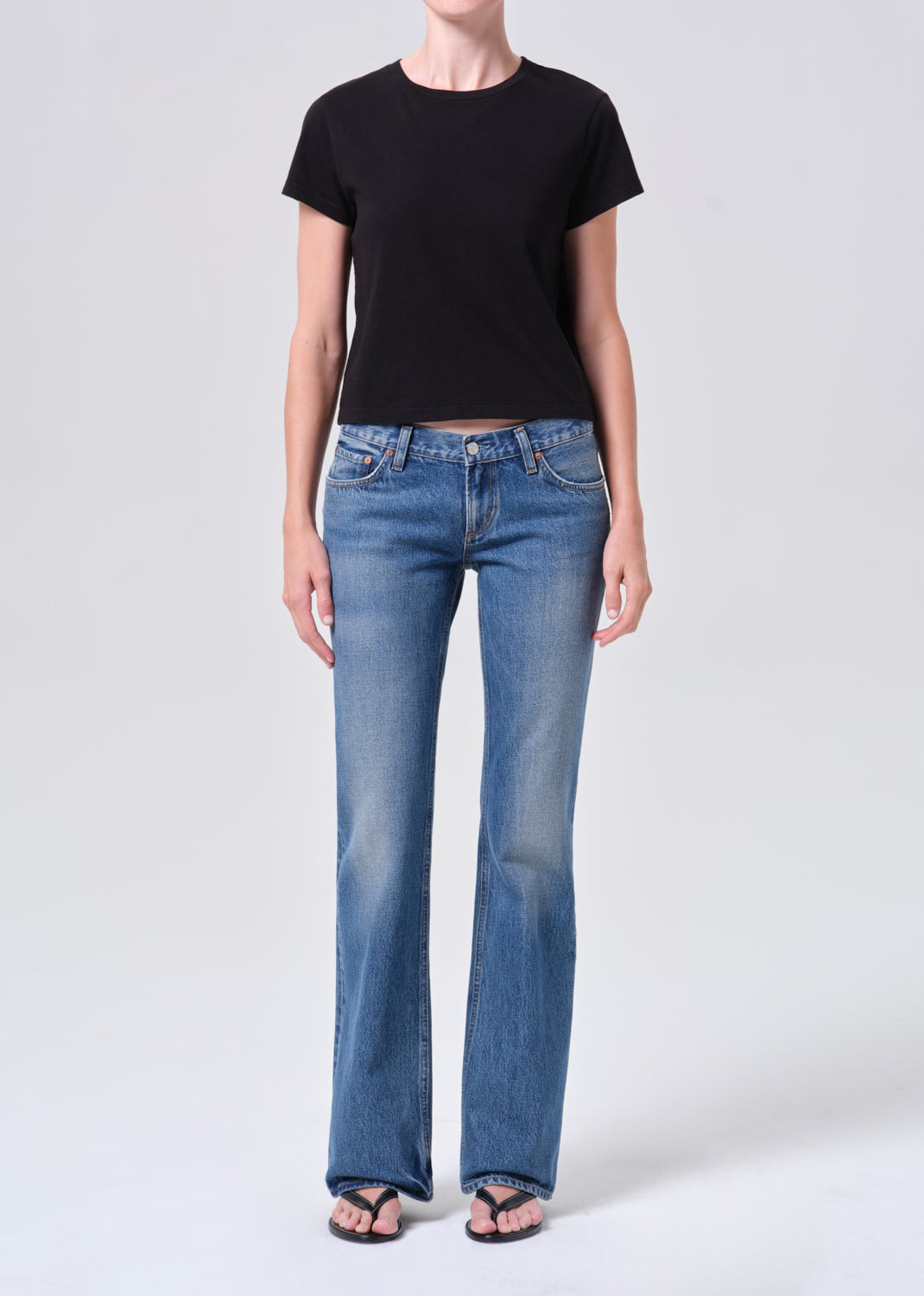 Person wearing a black t-shirt and blue jeans on a white background