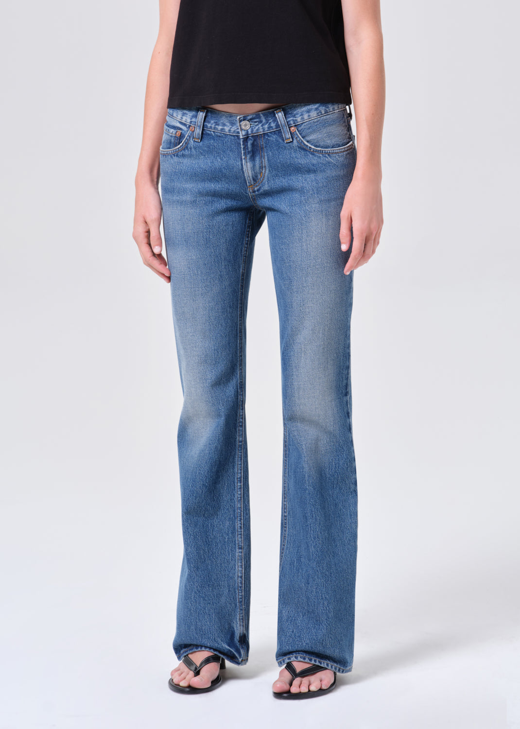 Person wearing blue flared jeans on a white background