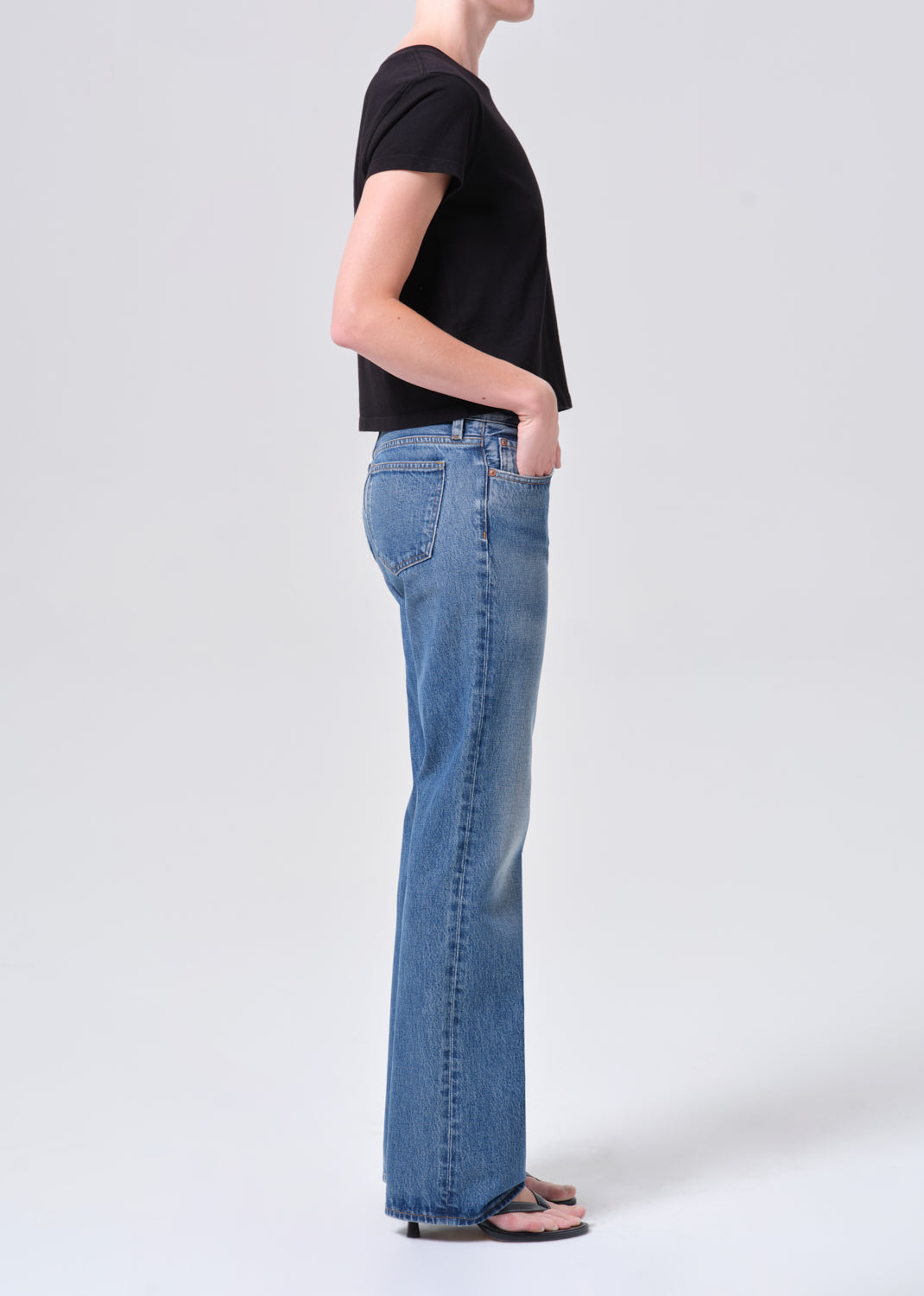 Person wearing blue jeans and a black shirt on a white background