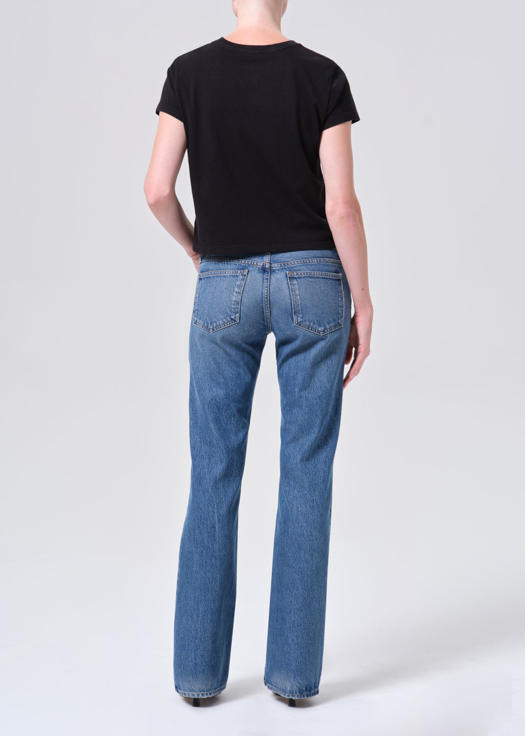 Person wearing blue jeans and a black t-shirt on a white background